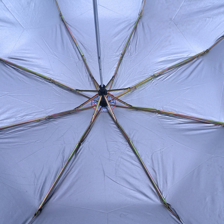 Close-up of an open umbrella with a light gray canopy and black handle.